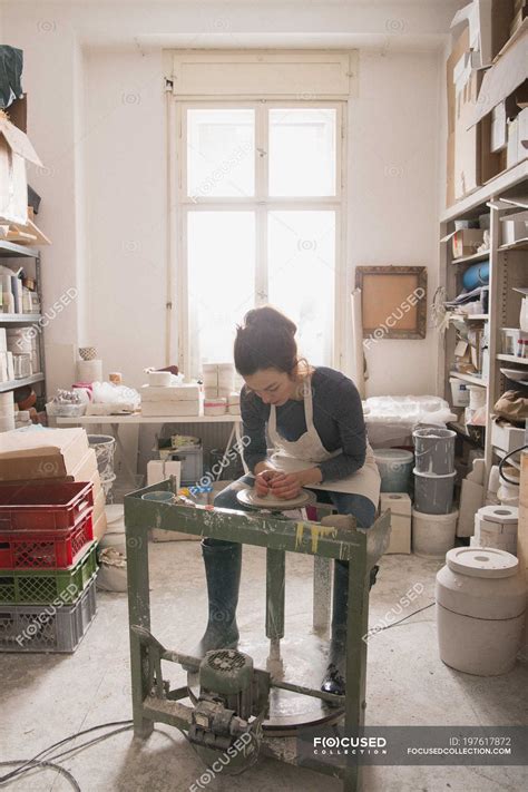 Caucasian woman is shaping pottery clay on a pottery wheel in a ceramic workshop. — design ...