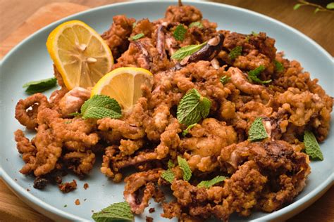 Dish Of Crispy Fried Breaded Baby Octopus Served With Lemon Slices And ...