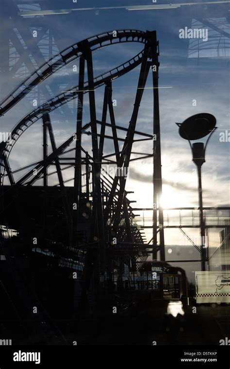 The roller coaster "Ring Racer" is reflected in a glass facade at the Nuerburgring at sunset in ...