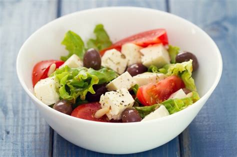 Premium Photo | Salad cheese with vegetables in white dish on blue background