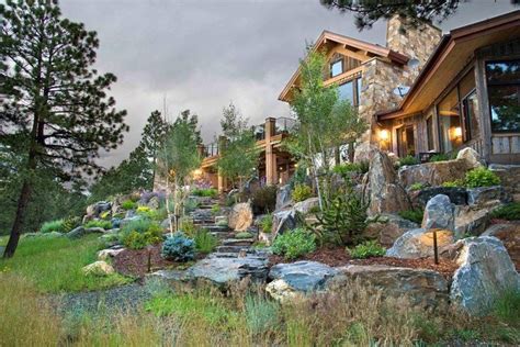 a large house with lots of rocks and trees in the front yard at night time