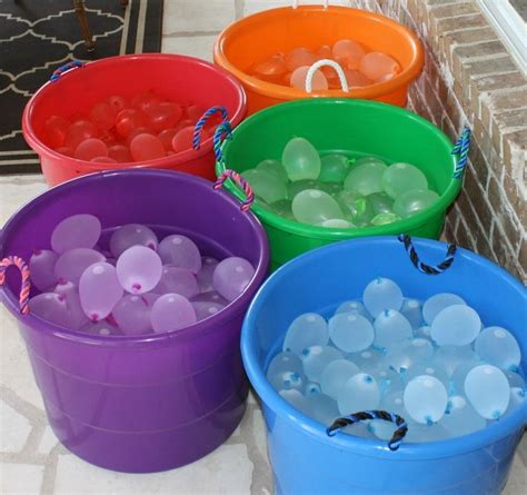 four buckets filled with water and balloons sitting on the ground next ...