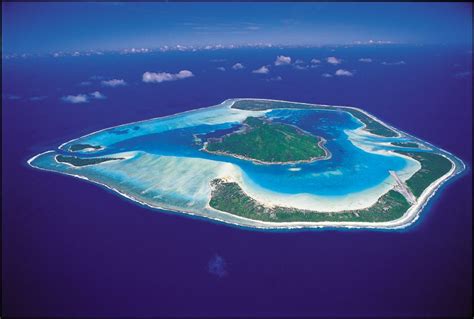 an island in the middle of the ocean with blue water and land on it's sides