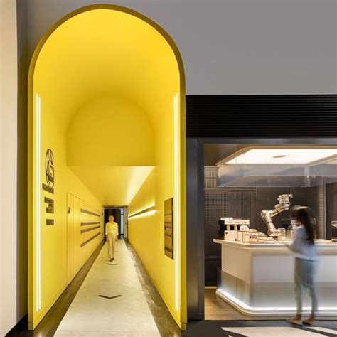 a person walking down a long hallway in a building with yellow lighting on the walls