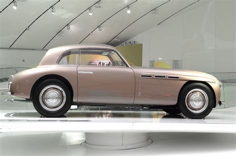 an old pink car is on display in a building with white walls and flooring