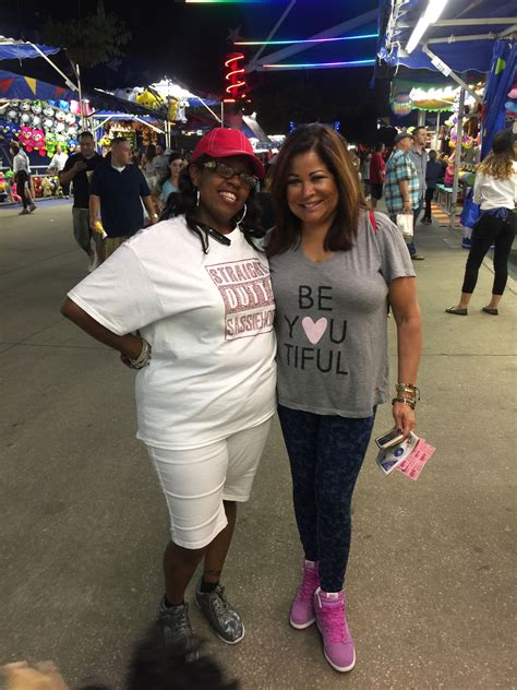 two women standing next to each other in front of a crowd at an outdoor ...