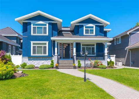 a blue house with white trim on the front and two story houses in the back