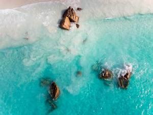 Aerial photography of crystal clear water at shore of Anse Lazio with its granite stone ...