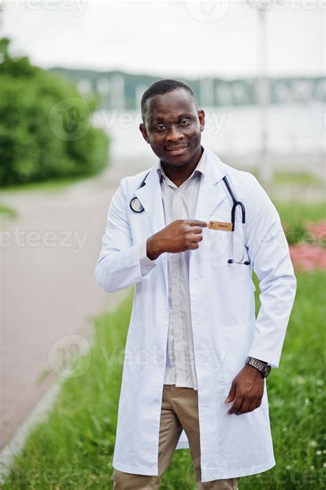 Young african american male doctor in white coat with a stethoscope posed outdoor. 10489092 ...