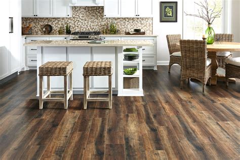 a kitchen with wood flooring and white cabinetry is shown in this image, there are wicker stools ...