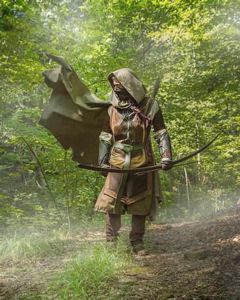 a man dressed in medieval clothing holding a bow and arrow while ...