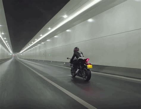 a man riding a motorcycle down a tunnel in the middle of road with ...