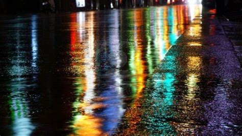 "Multi-colored lights glared on the wet road and cast eerie reflections, reminiscent of artistic ...