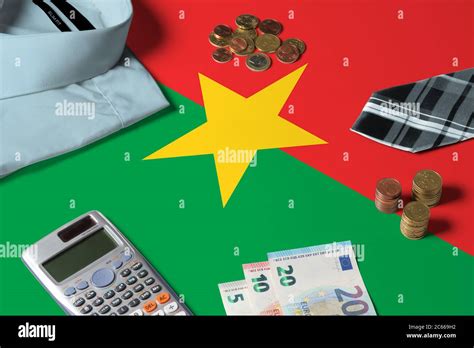 Burkina Faso flag on minimal money concept table. Coins and financial objects on flag surface ...