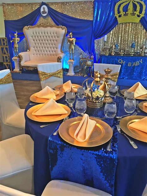 a table set up with blue and gold plates, silverware, and napkins