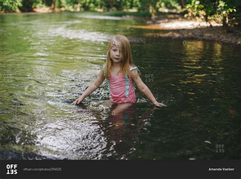 Little girl swimming in a river stock photo - OFFSET