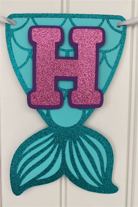 a mermaid tail with the letter h hanging from it's side on a door