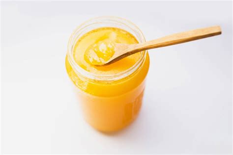 Hand holding a spoon of liquid honey over a Manuka honey jar - Creative Commons Bilder