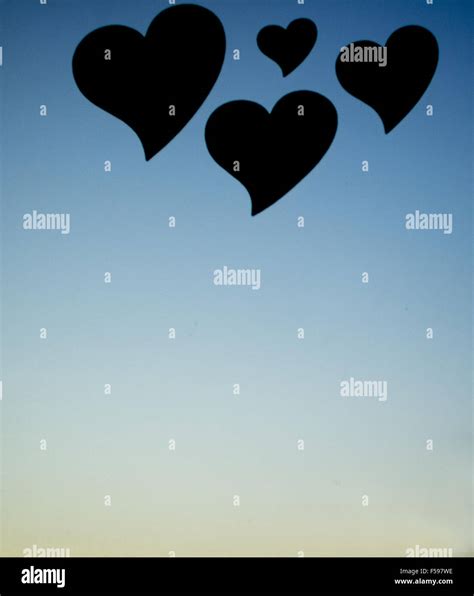 Four love heart shapes in silhouette floating in sunset sky background Stock Photo - Alamy