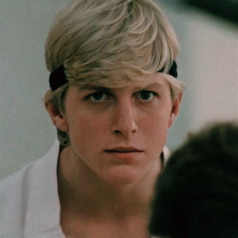 a young man with blonde hair wearing a white shirt and black bow tie looking at his reflection ...