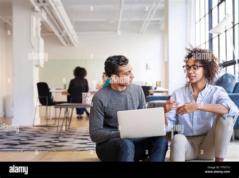 Business people talking while using laptop computer in office Stock Photo - Alamy