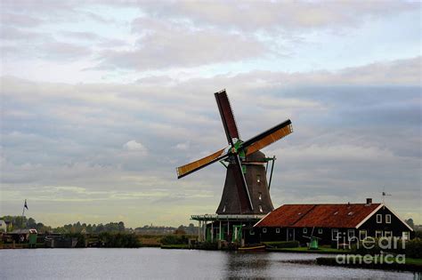 A sIngle dutch windmill with a traditional wooden house in a Netherland ...