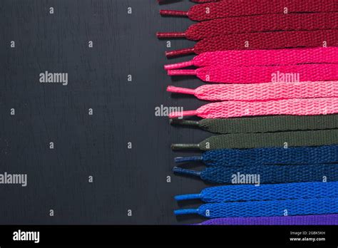 background of colored shoelaces on black wood, arranged horizontally, concept of perfection ...