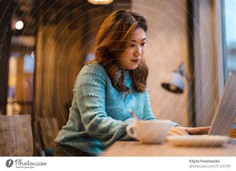 Young woman working on laptop in coffee shop - a Royalty Free Stock Photo from Photocase