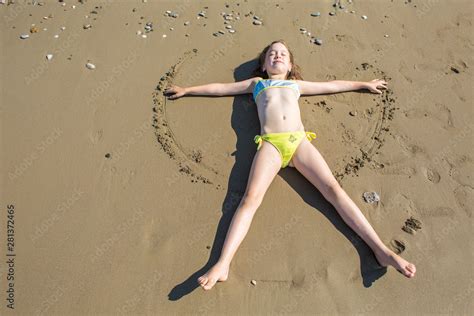 Little girl, closing her eyes, making sand angel on beach of Belek in ...