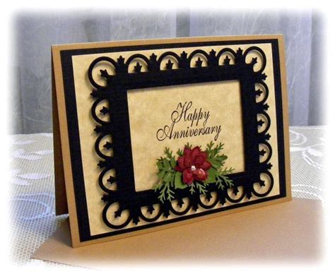 a card with an ornate frame and flowers on the front, says happy anniversary written in black ink