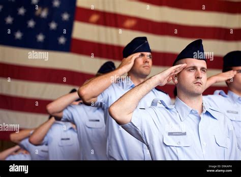 US Air Force Airmen salute to the American flag during the singing of the Star Spangled Banner a ...