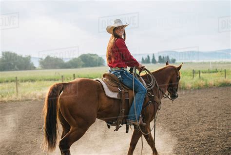 Caucasian cowgirl riding horse on ranch - Stock Photo - Dissolve