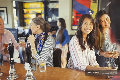 Women smiling at bartender and drinking at bar — people, cocktail ...