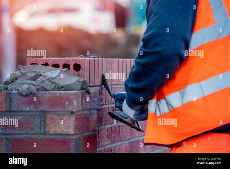 Close up of industrial bricklayer laying bricks on cement mix on construction site Stock Photo ...