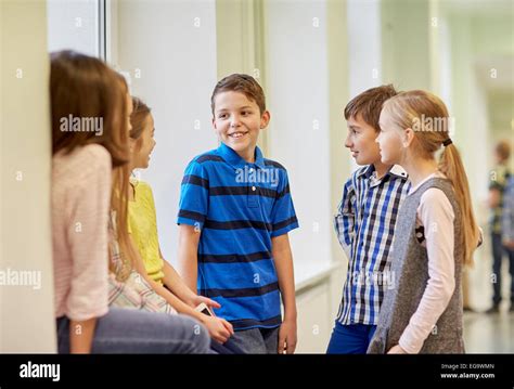 group of smiling school kids talking in corridor Stock Photo - Alamy