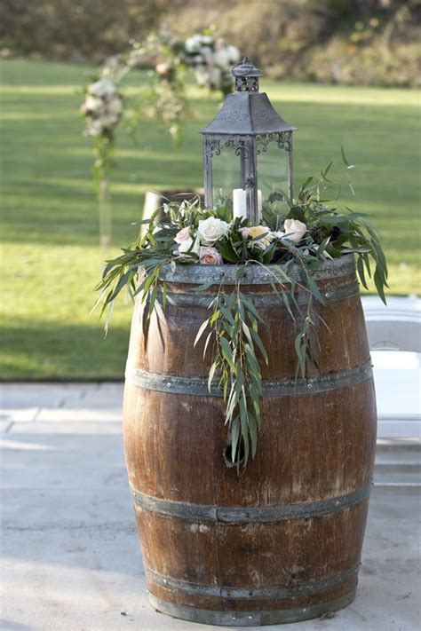 a wooden barrel with flowers and greenery on top is sitting in the ...