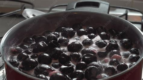 Cooking delicious red fruit jam, mixing and kneading. Close up ...