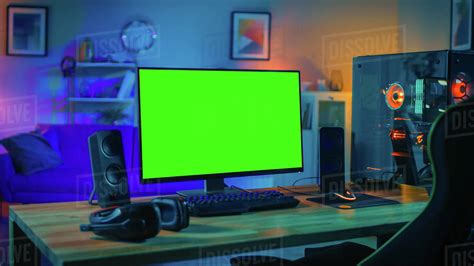 Powerful personal computer gamer rig with mock up green screen monitor stands on the table at ...