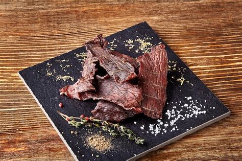 Premium Photo | Dried peppered beef jerky cut in strips on the black ...