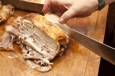 Man carving a half roast chicken - Free Stock Image