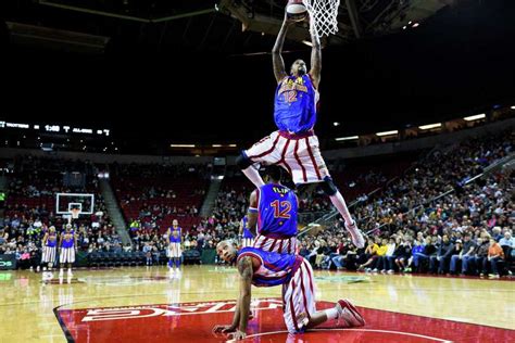 A Harlem Globetrotter slam dunks over a pile of other players on ...