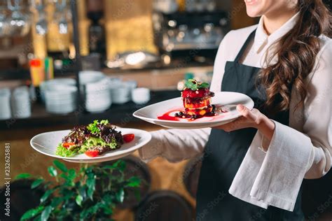 Waiter serving in motion on duty in restaurant. The waiter carries dishes Stock Photo | Adobe Stock