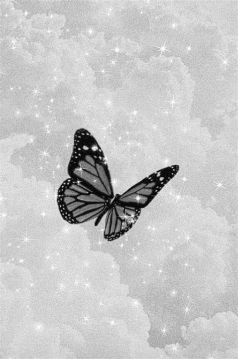 a black and white photo of a butterfly flying in the sky with stars ...