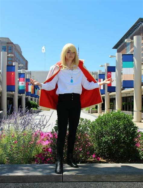 a woman with blonde hair wearing a red and white cape standing in front of flowers