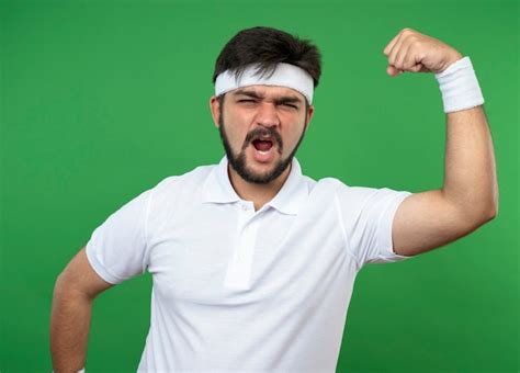 Free Photo | Excited young sporty man wearing headband and wristband showing strong gesture