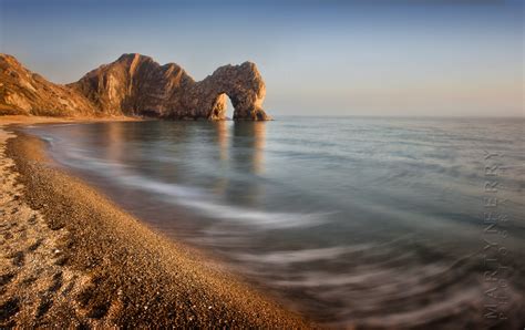 Classic sunset image of Durdle Door with long exposure