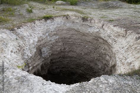 Black aperture of karst sinkhole, formed above abandoned limestone mine. Diameter about 15 ft ...