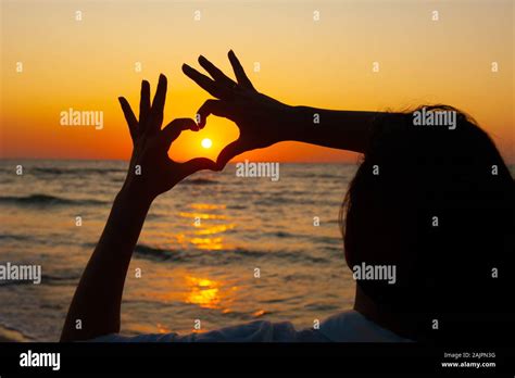 heart Sign with hands against the sunset, sunrise on the sea Stock Photo - Alamy