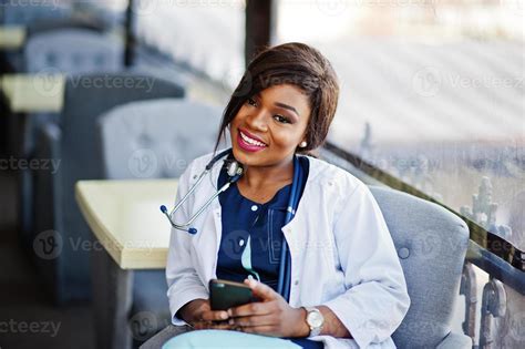 African american doctor female with stethoscope looked at phone and sitting on clinic. 10493665 ...