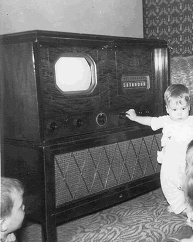 two children are playing with an old fashioned radio in the living room while another child watches